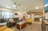 Open-concept lounge and kitchen in the Republic Palms clubhouse with plush seating, puzzle tables, full kitchen appliances, and light wood floors.