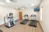 Republic Palms Apartments fitness center with treadmills, elliptical machine, mounted TV, and wood-style flooring in a bright, modern setting.