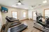 Bright, modern gym featuring treadmills and elliptical machines, with wood-style flooring and ceiling fans for comfort.