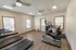 Compact fitness room with cardio machines and windows providing natural light&mdash;ideal for convenient workouts close to home.