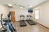 Two treadmills and an elliptical facing a wall-mounted TV in a clean, air-conditioned space for resident use.
