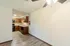 View of the kitchen and adjacent dining area with wooden cabinets, marbled countertops, and black appliances. A ceiling fan with lights hangs in the dining area, and the wood-patterned flooring extends throughout, creating a cohesive and open feel in the space.