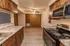 Kitchen in Polo Club apartments showing granite-style countertops, wood cabinetry, and a view into the dining area with a ceiling fan.