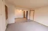 A cozy living space transitioning into a dining area with a ceiling fan. The front door is on the right, and a small hallway leads to additional rooms.