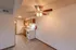 A compact kitchen with wooden cabinetry, a white electric stove, and a white refrigerator. A ceiling fan with lights is positioned in the dining space.