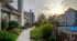 Cobblestone Village community walkway at sunset, showcasing landscaped grounds, the resident pool area, and multi-level apartment buildings.