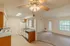 Bright open-concept kitchen and living room in a 1-bedroom unit at Cobblestone Village, featuring vaulted ceilings, a ceiling fan with light fixture, neutral carpeting, and access to a private patio through a glass door.