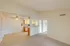 View from the living room into the kitchen and dining area, showcasing an open floor plan with distinct tile and carpet flooring, crown molding detail, and a ceiling fan centered above the dining nook.