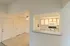 Cut-out kitchen bar overlooking the living area, creating an open and connected feel between the cooking space and the rest of the apartment; decorated in soft neutral tones with natural light filtering in.