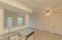 Kitchen sink and bar area with dual stainless steel basins and a high-arc faucet, facing the living room with views out the window and glass door leading to the balcony.