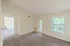 Spacious living room with plush carpeting, large front-facing window, and vaulted ceilings, providing a bright and airy feel with plenty of natural light.