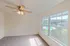 Spacious bedroom with plush carpeting, a large window with horizontal blinds, and a ceiling fan providing both comfort and natural light.