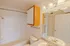 Full bathroom with a tub and shower combo, featuring a curved curtain rod, chrome grab bar, and soft lighting over a wide mirror.