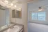 Wide-angle shot showing both the bathroom and bedroom, highlighting the convenient layout, carpet transition, and soft lighting.