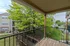 Balcony view of the community grounds with lush green spaces, central clubhouse, and multi-level apartment buildings in the background.