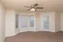 Bright living room with bay windows, ceiling fan, and private patio door at Embassy Ozark Apartments.