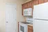 Compact kitchen featuring white appliances, overhead microwave, and wood cabinetry at Embassy Ozark.
