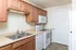 Full kitchen layout with double sink, dishwasher, white appliances, and ample cabinet storage at Embassy Ozark.