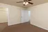 Bedroom at Embassy Ozark Apartments in Ozark, MO, with brown carpet, ceiling fan with lights, walk-in closet, and two white doors leading to the hallway and closet. Walls are painted a soft neutral color with white trim.