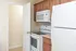 Compact kitchen featuring white appliances, overhead microwave, and wood cabinetry at Embassy Ozark.