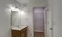 Bathroom with double-sink vanity, well-lit mirror, and access to a large walk-in closet at Embassy Ozark Apartments.