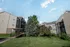 Spacious, tree-lined courtyard between apartment buildings at Cobblestone Village, designed for tranquil senior living with scenic walking paths and greenery.