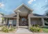 Cobblestone Village leasing center in Springfield, MO with stone pillars, a peaked roof, and double red entry doors, welcoming visitors to this 55+ living community.