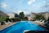 Large outdoor pool surrounded by lounge chairs and umbrellas at Cobblestone Village, a 55+ community offering relaxing recreation for active senior residents.