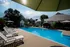 Sparkling outdoor pool at Cobblestone Village 55+ community in Springfield, MO, surrounded by white lounge chairs and shaded seating areas with large umbrellas&mdash;offering a relaxing, resort-style experience for senior residents.