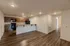 Open-concept kitchen with wood cabinetry, black appliances, and a breakfast bar overlooking the dining area at Republic Palms Apartments in Republic, MO. Durable wood-style flooring extends throughout the space.