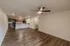 Expansive living area at Republic Palms Apartments in Republic, MO, showcasing wood-style flooring, a ceiling fan, and an open kitchen with modern cabinetry and black appliances.