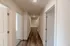Long hallway at Republic Palms Apartments in Republic, MO, featuring wood-style flooring, white doors to bedrooms and storage closets, and soft overhead lighting.