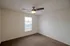 Spacious bedroom at Republic Palms Apartments in Republic, MO, featuring plush brown carpet, neutral walls, a ceiling fan with light,