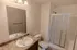 Bathroom with stand-up shower &ndash; Secondary bathroom at Republic Palms Apartments in Republic, MO, with a walk-in shower featuring sliding glass doors, a white vanity with speckled countertop, chrome faucet, and large wall mirror.