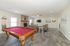 Spacious living room with a luxurious pool table, cozy seating area, and elegant fireplace, perfect for entertainment and relaxation.