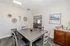 Bright dining area with modern gray table set, chic wall decor, and inviting open doorway leading to cozy living room.