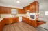 Kitchen with extensive wood cabinetry, double sink, dishwasher, electric cooktop, wall oven, and adjoining living area.
