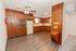 Vintage style kitchen at East Manor Apartments with warm wood cabinetry, wood look flooring, white appliances, and a ceiling fan.