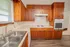 Close view of the kitchen featuring a double basin sink, electric cooktop, wall oven, wood cabinets, and neutral countertops.