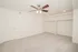Alternate view of the bedroom featuring a ceiling fan, light carpet, and two open closets with shelving and hanging rods.
