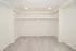 Close view of the bedroom&rsquo;s double open closets with built in shelving, hanging rods, recessed lighting, and carpeted storage space.