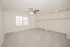 Spacious bedroom at East Manor Apartments with light carpet, a ceiling fan, large window, recessed lighting, and open closet space.