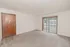 Bright living room at El Madrid Apartments with neutral carpet, private balcony access, and a wood entry door.