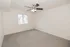 Carpeted bedroom with a window, ceiling fan, and neutral walls at El Madrid Apartments in Springfield, Missouri.