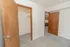 Bedroom with an open walk in closet, neutral carpet, and access to the kitchen and living area.