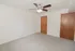 Carpeted bedroom with neutral walls, a ceiling fan, and wood doors at El Madrid Apartments in Springfield, Missouri.