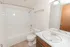Bathroom with a tub and shower combination, wood vanity, large mirror, and brushed nickel fixtures.
