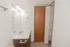 Bathroom vanity with a large mirror, brushed nickel fixtures, and an open linen closet with built in shelving.