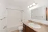 Bright and modern bathroom featuring elegant lighting, a spacious vanity with a granite countertop, and a pristine bathtub for a relaxing experience.