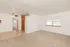 Inviting open living space with plush carpeting, large windows for natural light, and a convenient ceiling fan for comfort.